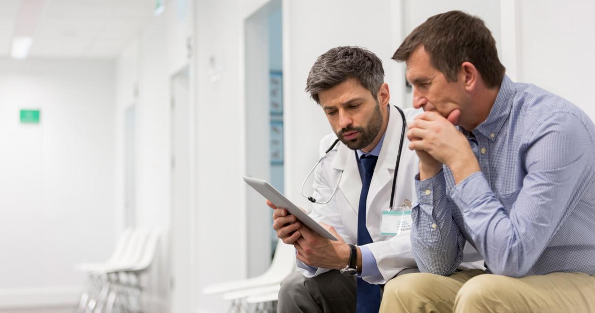 Physician and a man reviewing something on an tablet