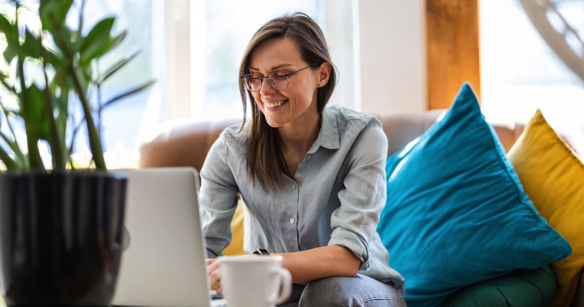 Woman sitting on couch typing on laptop