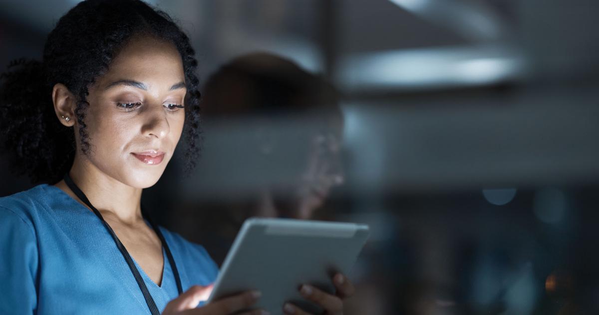 A female physician holding and looking at a tablet 