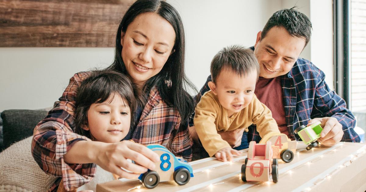 A young couple playing happily with their young kids  