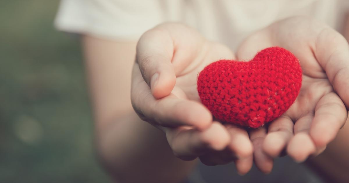 Two hands holding a crocheted heart 