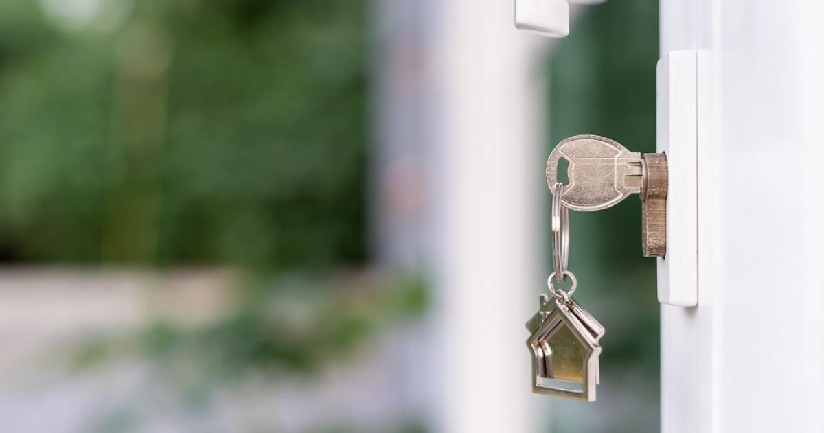 Image of a silver key in a lock with a house on the key chain