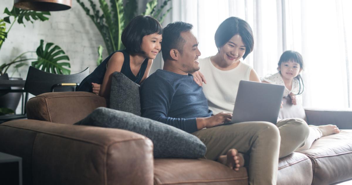 Group of people looking at a laptop while sitting on a couch