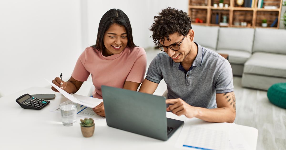 Young couple with a laptop, calculator, and papers at a counter