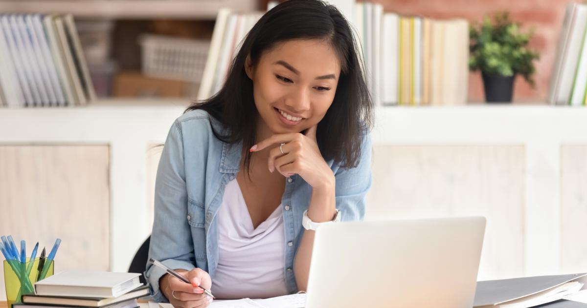 Young woman with notepads looking at laptop