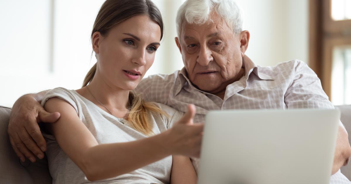 Woman helping an older man on a computer