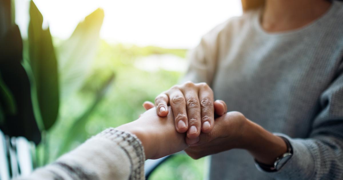 Person holding another person's hand comfortingly