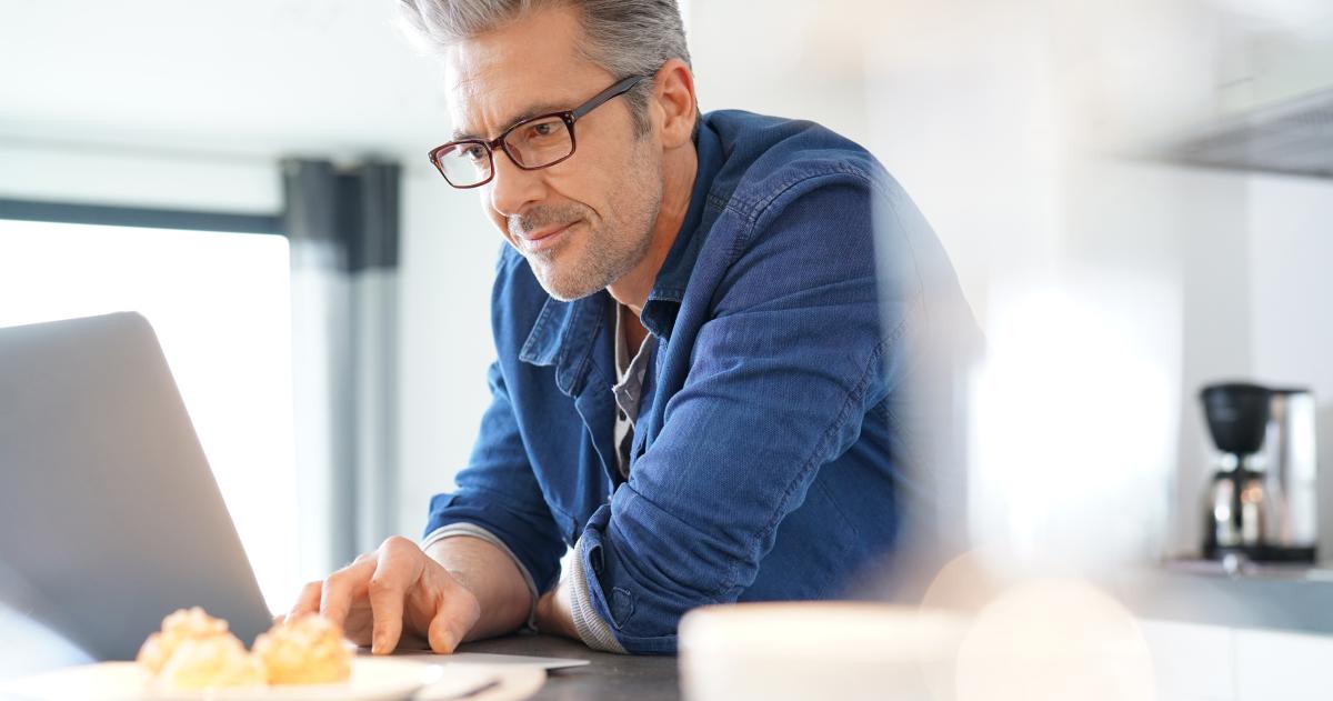 Man in blue shirt and glasses working on laptop