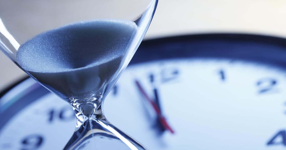 An hour glass atop a clock