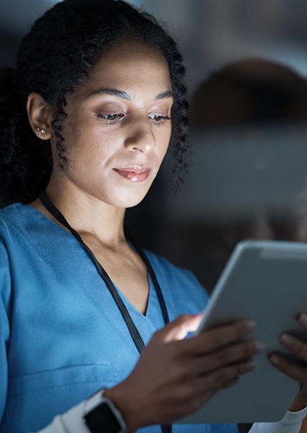Female Physician looking at a tablet as it illuminates her face